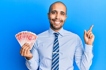 Wall Mural - Hispanic adult man holding 20 israel shekels banknotes smiling happy pointing with hand and finger to the side