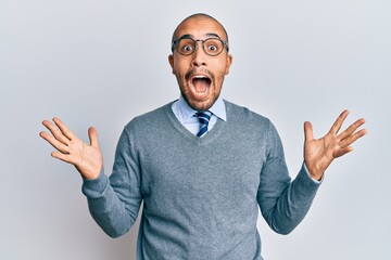 Canvas Print - Hispanic adult man wearing glasses and business style celebrating crazy and amazed for success with arms raised and open eyes screaming excited. winner concept