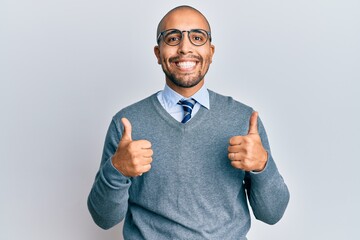 Wall Mural - Hispanic adult man wearing glasses and business style success sign doing positive gesture with hand, thumbs up smiling and happy. cheerful expression and winner gesture.