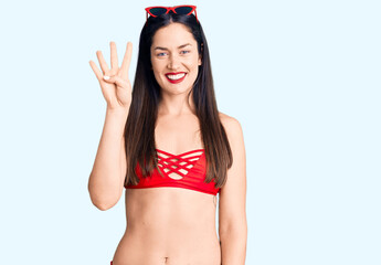 Canvas Print - Young beautiful caucasian woman wearing bikini showing and pointing up with fingers number four while smiling confident and happy.