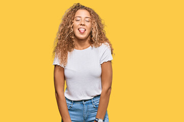 Poster - Beautiful caucasian teenager girl wearing casual white tshirt sticking tongue out happy with funny expression. emotion concept.