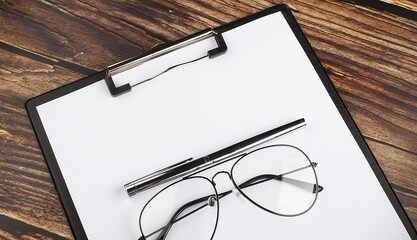 Poster - blank clipboard with a pen and glasses isolat on wooden background
