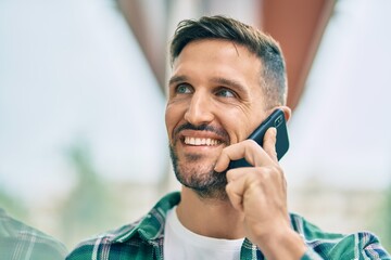 Wall Mural - Young caucasian man smiling happy talking on the smartphone at the city.