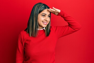 Poster - Young latin woman wearing casual clothes very happy and smiling looking far away with hand over head. searching concept.