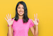 Beautiful asian young woman wearing casual pink t shirt showing and pointing up with fingers number eight while smiling confident and happy.