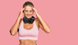 © Krakenimages.com - Young blonde woman wearing gym clothes and using headphones with hand on head for pain in head because stress. suffering migraine.