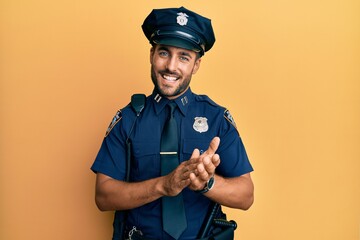 Canvas Print - Handsome hispanic man wearing police uniform clapping and applauding happy and joyful, smiling proud hands together