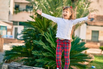 Adorable caucasian child girl with open arms  smiling happy at the city.