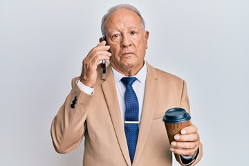 Sticker - Senior caucasian man talking on the smartphone and drinking a cup of coffee relaxed with serious expression on face. simple and natural looking at the camera.