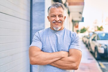 Sticker - Middle age hispanic grey-haired man with crossed arms smiling happy at the city.