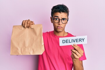 Sticker - Young handsome african american man holding take away paper bag with delivery text skeptic and nervous, frowning upset because of problem. negative person.