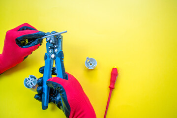 Wall Mural - Electrician peeling off insulation from wires - closeup on hands and pliers