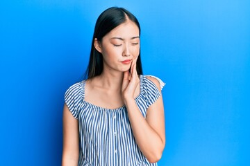 Canvas Print - Young chinese woman wearing casual striped t-shirt touching mouth with hand with painful expression because of toothache or dental illness on teeth. dentist