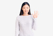 © Krakenimages.com - Young beautiful chinese woman wearing casual sweater showing and pointing up with fingers number five while smiling confident and happy.