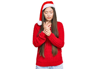 Canvas Print - Young chinese woman wearing christmas hat suffering pain on hands and fingers, arthritis inflammation