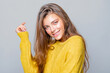 © Julia - Portrait of beautiful happy girl smile in yellow sweater and looks at the camera, smiling on a gray background. close-up. positive cute girl with curly hair. makeup.