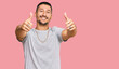© Krakenimages.com - Handsome man with tattoos wearing 90s style approving doing positive gesture with hand, thumbs up smiling and happy for success. winner gesture.