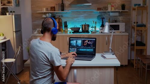 Creative filmmaker editing video footage in home using modern technology. Man content creator in home working on montage of film in new software for editing late at night.