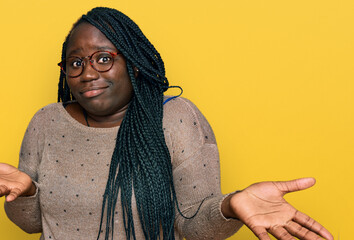 Sticker - Young black woman with braids wearing casual clothes and glasses clueless and confused expression with arms and hands raised. doubt concept.