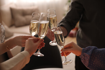 People clinking glasses with champagne at home, closeup