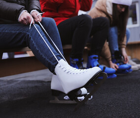 Canvas Print - Young woman wearing white ice skates on bench outdoors, closeup