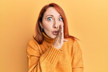 Canvas Print - Beautiful redhead woman wearing casual winter sweater over yellow background hand on mouth telling secret rumor, whispering malicious talk conversation