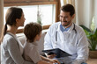 © fizkes - Smiling caring male pediatrician talk consult small boy patient at consultation in hospital with mother. Happy doctor do checkup examine little child at visit to clinic with mom. Healthcare concept.