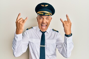 Poster - Handsome middle age mature man wearing airplane pilot uniform shouting with crazy expression doing rock symbol with hands up. music star. heavy music concept.