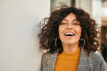 Young hispanic businesswoman smiling happy standing at the city.