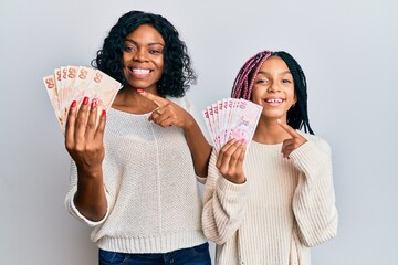 Poster - Beautiful african american mother and daughter holding turkish lira banknotes smiling happy pointing with hand and finger