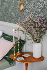 White vase with dried flowers on the table near the bed in the bedroom