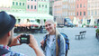 © art24pro - Medium shot of man making photos of female tourist on the view of city market square. Blonde woman making faces and smiling.