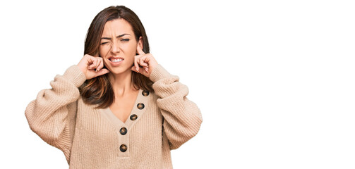 Wall Mural - Young brunette woman wearing casual winter sweater covering ears with fingers with annoyed expression for the noise of loud music. deaf concept.