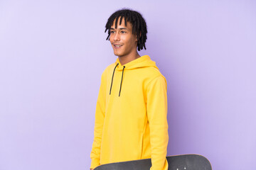 Wall Mural - Young african american man isolated on purple background with a skate