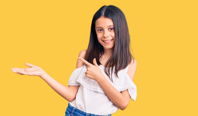 Sticker - Beautiful child girl wearing casual clothes amazed and smiling to the camera while presenting with hand and pointing with finger.