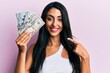 © Krakenimages.com - Beautiful hispanic woman holding dollars smiling happy pointing with hand and finger