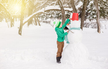 Wall Mural - Happy young boy  is making a snowman. Empty space for text