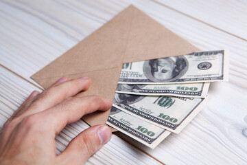 Wall Mural - US dollars in an envelope on a wooden table. Income, bonuses or bribes concept.