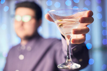 Caucasian man holding glass of martini with olive on background