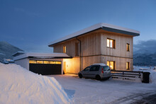 View Of Single-family House With Garage In Snow-covered Winter With Cleared Entrance At Night
