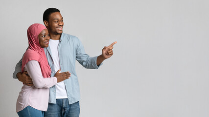 Canvas Print - Joyful black guy showing his girlfriend in hijab advertisement