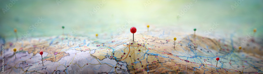 Pins on a geographic map curved like mountains. Pinning a location on a map with mountains. Adventure,  geography, mountaineering, hike and travel concept background. - obrazy, fototapety, plakaty 