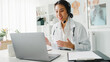 © tirachard - Young Asia lady doctor in white medical uniform with stethoscope using computer laptop talking video conference call with patient at desk in health clinic or hospital. Consulting and therapy concept.