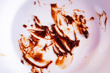 Close up view of dirty white plate eaten chocolate sauce stain. Finished chocolate cake. Concept of enjoy eating.