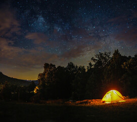 a camping tent under milky way sky and twilight at night