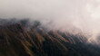 © Scopio - Brown and green mountains covered with white clouds