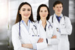 © rogerphoto - Group of young professional doctors standing as a team with arms crossed in sunny hospital. Medical help, insurance in health care, best disease treatment and medicine concept