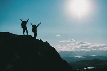 Wall Mural - Silhouettes of two hikers on mountain top