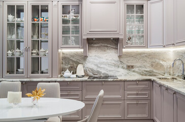 Modern beige and grey colored kitchen interior in classic style with dining table in luxury home