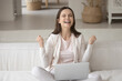 © fizkes - Overjoyed young Caucasian woman sit on sofa at home feel euphoric win online lottery on laptop. Happy excited millennial female triumph read good promotion news on web. Success concept.